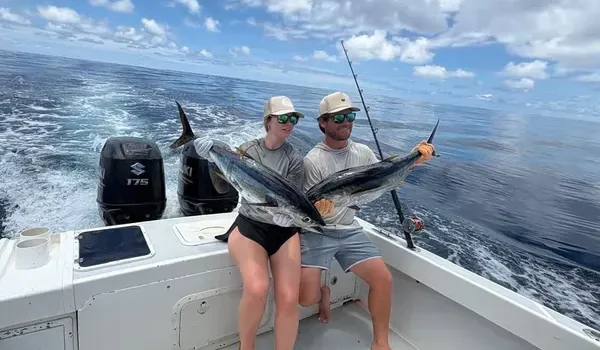 Couple proudly displaying two yellowfin tuna aboard a luxury sportfishing boat in Costa Rica on a sunny day.